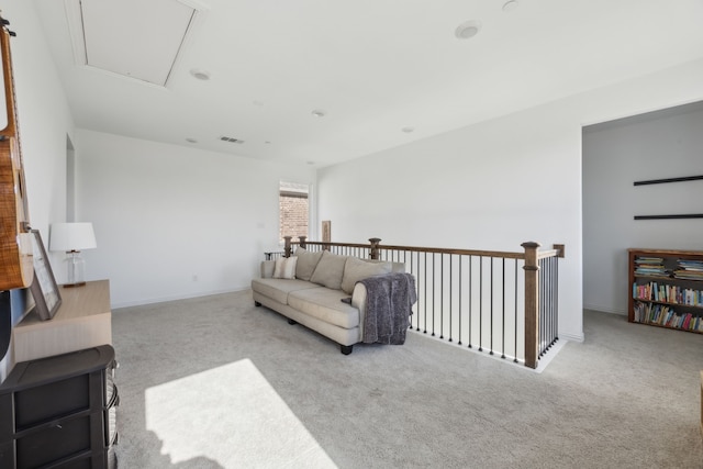 living area featuring visible vents, light carpet, attic access, and baseboards