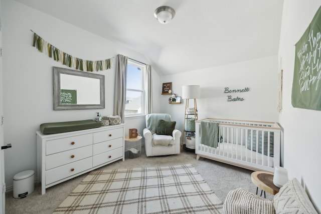 bedroom with lofted ceiling, a nursery area, and light colored carpet