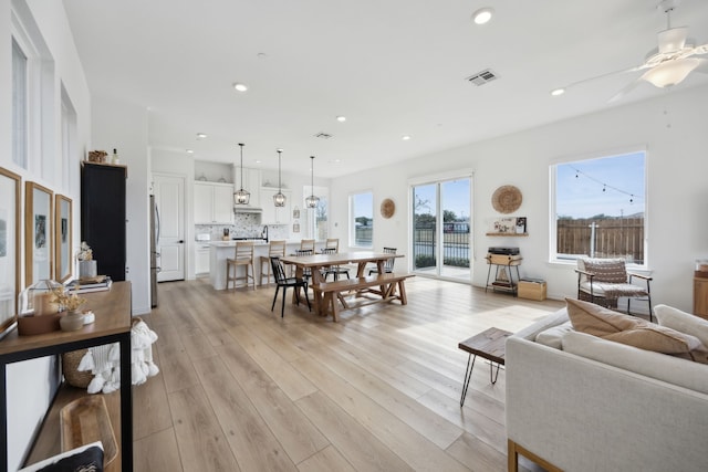 living area with light wood-type flooring, visible vents, ceiling fan, and recessed lighting