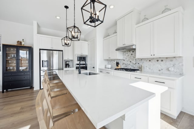 kitchen with light countertops, a center island with sink, and white cabinetry