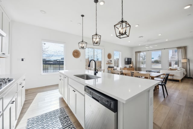 kitchen with a center island with sink, stainless steel appliances, light countertops, open floor plan, and a sink