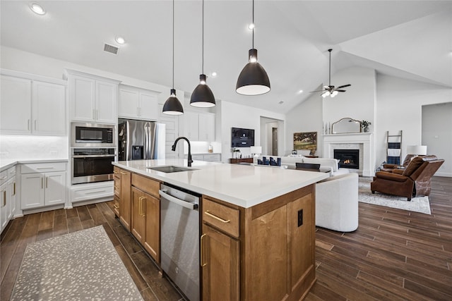 kitchen featuring light countertops, appliances with stainless steel finishes, open floor plan, white cabinets, and a sink