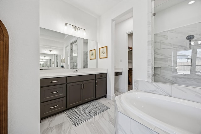 bathroom featuring tiled shower, marble finish floor, a walk in closet, vanity, and a bath