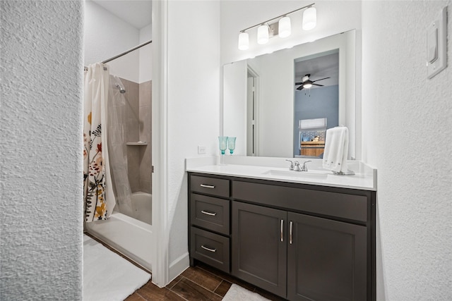 bathroom with a ceiling fan, a textured wall, wood tiled floor, shower / bath combo with shower curtain, and vanity