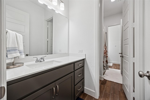 full bath with baseboards, vanity, and wood tiled floor