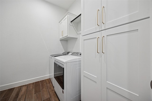 laundry area featuring dark wood-style flooring, washing machine and clothes dryer, cabinet space, and baseboards