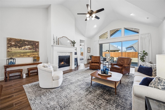 living room featuring baseboards, dark wood finished floors, a ceiling fan, a glass covered fireplace, and high vaulted ceiling