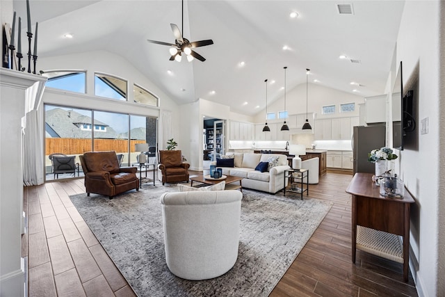 living area with dark wood-type flooring, visible vents, ceiling fan, and high vaulted ceiling