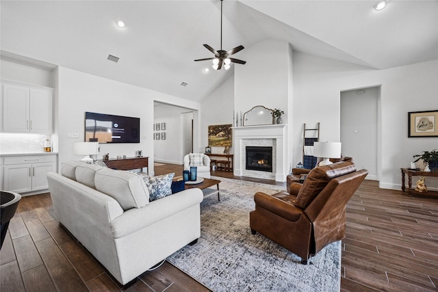 living area featuring high vaulted ceiling, visible vents, dark wood finished floors, and a stone fireplace