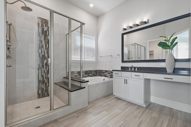 full bathroom featuring wood finished floors, a stall shower, vanity, and a bath