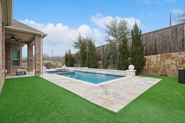 view of swimming pool with ceiling fan, a fenced backyard, a pool with connected hot tub, a yard, and a patio area