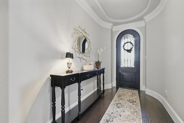 entryway with a tray ceiling, arched walkways, dark wood-type flooring, ornamental molding, and baseboards