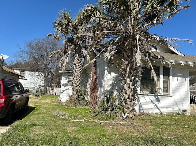 view of side of property with crawl space and a lawn