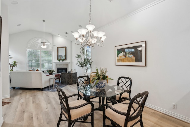 dining space with light wood finished floors, baseboards, a glass covered fireplace, ceiling fan, and vaulted ceiling