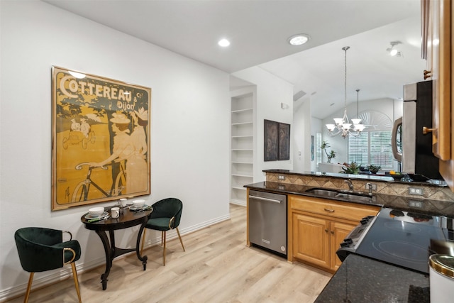 kitchen featuring light wood finished floors, dishwasher, dark stone countertops, hanging light fixtures, and a sink