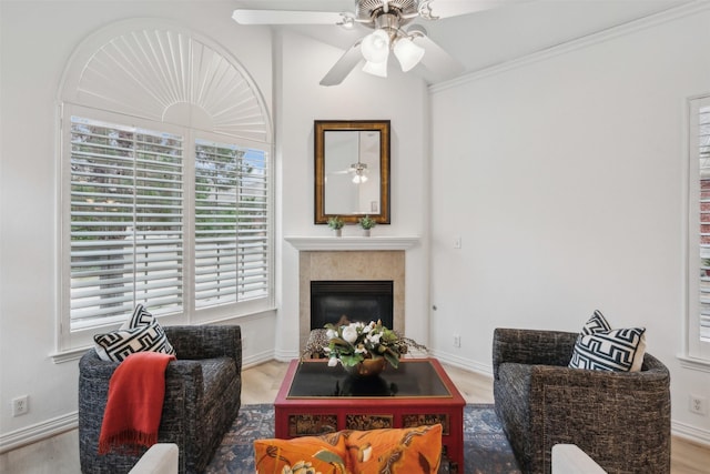 living room with ceiling fan, a premium fireplace, wood finished floors, and baseboards