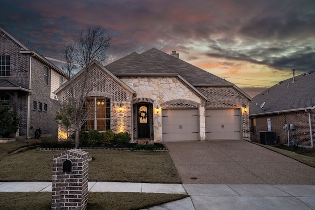 french country home featuring central AC unit, a garage, brick siding, concrete driveway, and a front yard