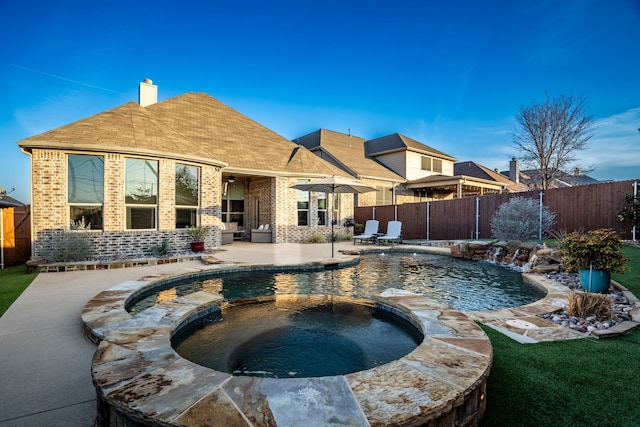 rear view of property featuring brick siding, a chimney, and a fenced backyard