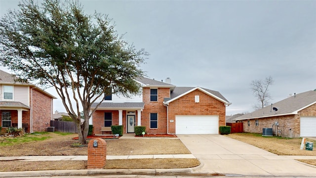 traditional home with brick siding, an attached garage, fence, cooling unit, and driveway