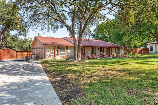 ranch-style house featuring brick siding, a porch, a front yard, and fence