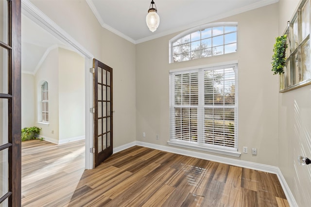 empty room featuring ornamental molding, baseboards, and wood finished floors