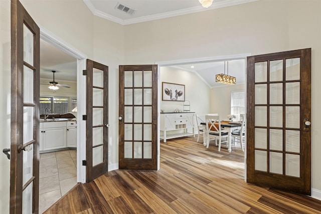 entryway with visible vents, ornamental molding, a sink, wood finished floors, and french doors