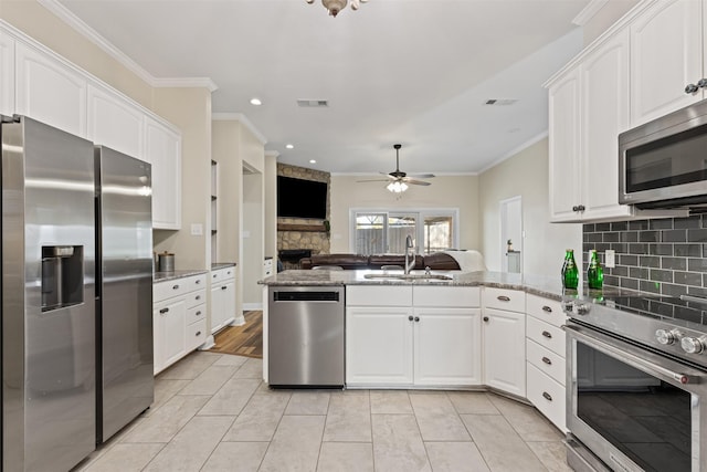 kitchen featuring visible vents, crown molding, a peninsula, stainless steel appliances, and a sink