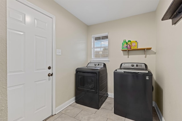 laundry area featuring laundry area, light tile patterned floors, separate washer and dryer, and baseboards