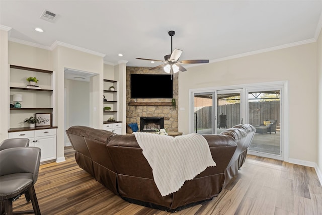 living area featuring visible vents, built in shelves, wood finished floors, and ornamental molding