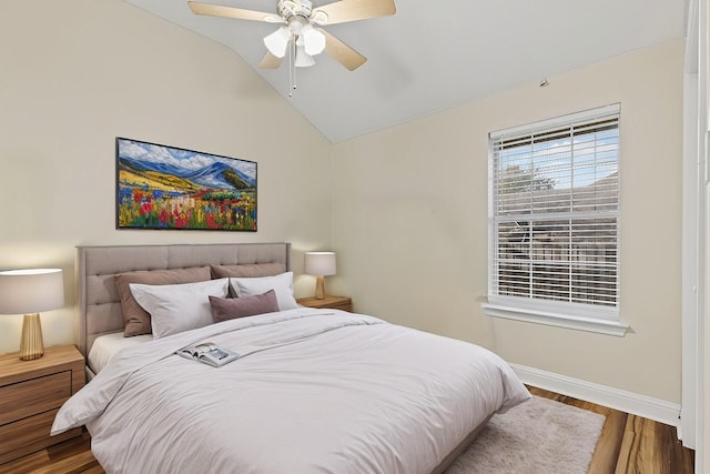 bedroom with ceiling fan, baseboards, wood finished floors, and vaulted ceiling