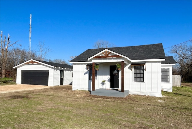 modern farmhouse with a detached garage, a shingled roof, board and batten siding, a front yard, and an outdoor structure