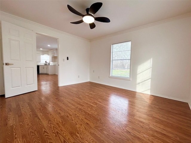 empty room with a ceiling fan, crown molding, baseboards, and wood finished floors