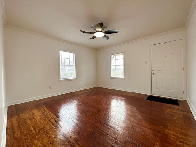 spare room featuring crown molding, dark wood-type flooring, baseboards, and a healthy amount of sunlight