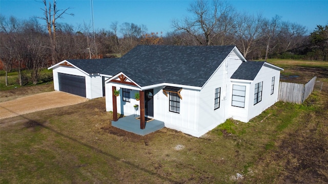 modern farmhouse style home with a shingled roof, fence, a front lawn, and concrete driveway