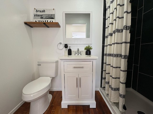 bathroom with toilet, a stall shower, vanity, wood finished floors, and baseboards