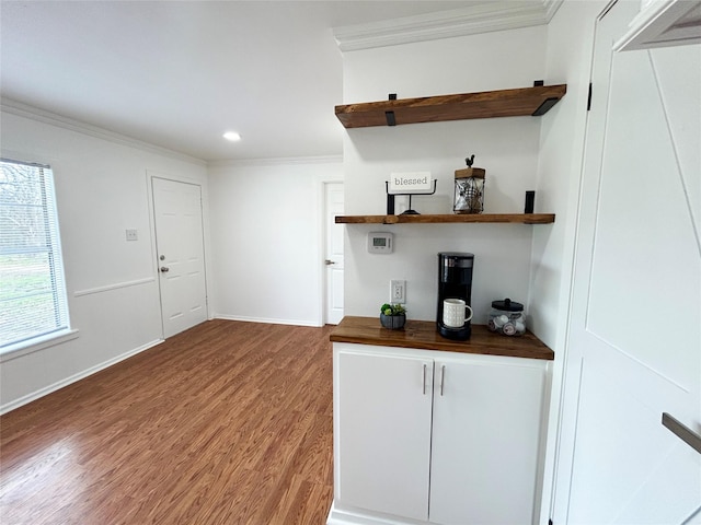 bar featuring recessed lighting, crown molding, baseboards, and wood finished floors