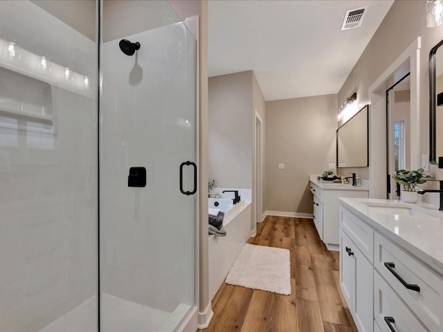 full bathroom with visible vents, wood finished floors, a garden tub, a shower stall, and a sink