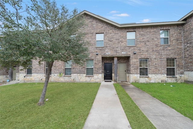 view of front of property featuring stone siding, brick siding, and a front lawn