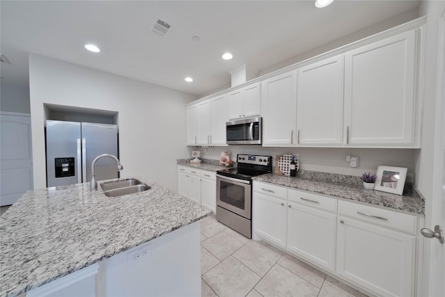 kitchen with light stone counters, visible vents, appliances with stainless steel finishes, white cabinets, and a sink