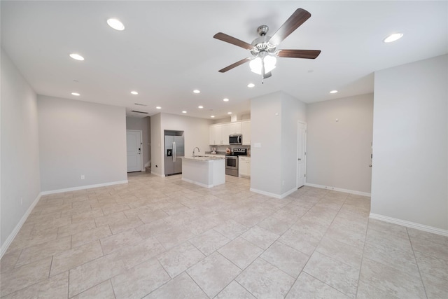 unfurnished living room with baseboards, a sink, and recessed lighting