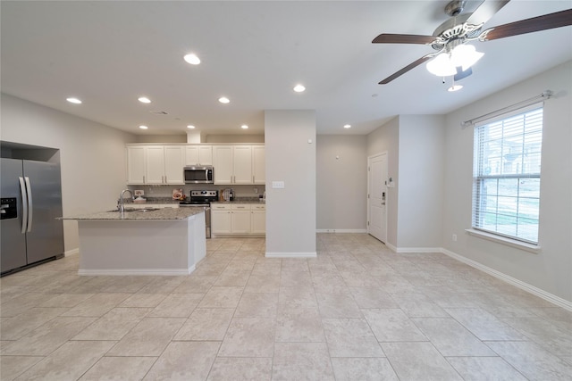 kitchen featuring a center island with sink, white cabinets, light stone countertops, stainless steel appliances, and recessed lighting