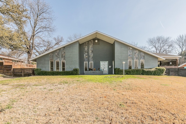 rear view of house featuring a lawn and fence