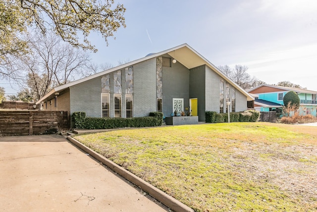 exterior space featuring fence, a lawn, and brick siding