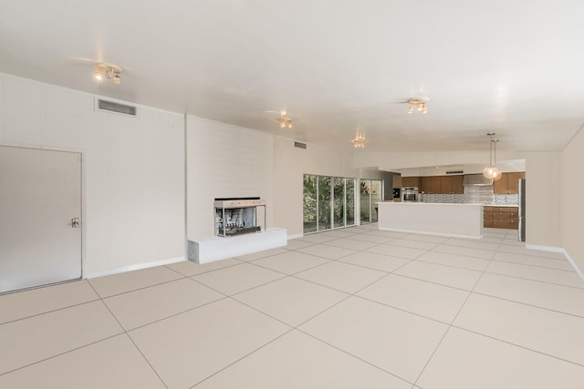 unfurnished living room featuring light tile patterned floors, a large fireplace, and baseboards