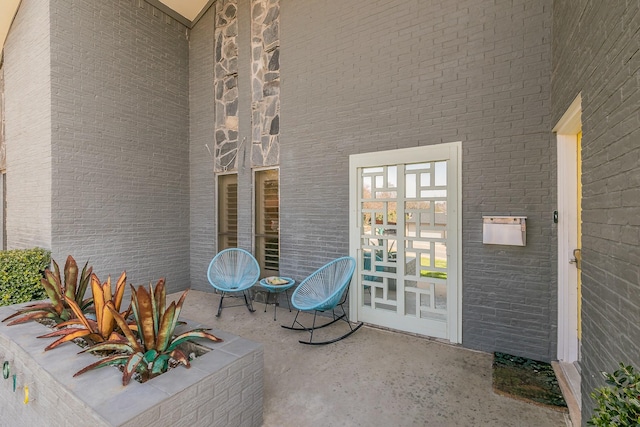 view of exterior entry with brick siding, a patio area, and french doors