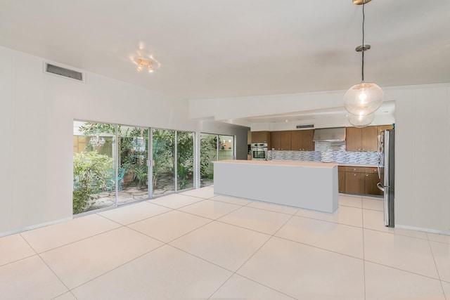 kitchen with appliances with stainless steel finishes, light countertops, light tile patterned flooring, and tasteful backsplash