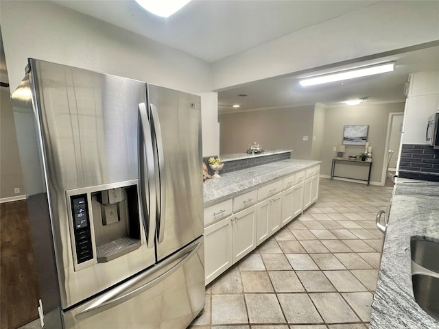 kitchen with light tile patterned floors, light stone counters, white cabinetry, appliances with stainless steel finishes, and crown molding