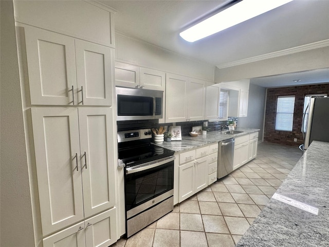 kitchen featuring light tile patterned floors, a sink, white cabinets, appliances with stainless steel finishes, and light stone countertops