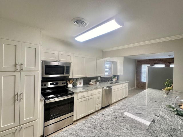 kitchen with visible vents, white cabinets, light stone countertops, stainless steel appliances, and a sink