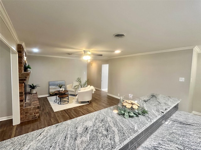 living room featuring dark wood-style floors, visible vents, a fireplace, and ornamental molding